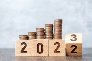 Stacks of coins sitting on top of blocks that are turning from 2022 to 2023.