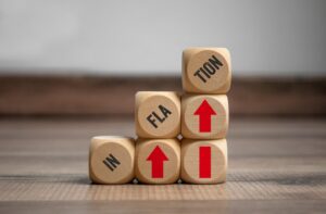 Dice stacked upward with red arrows and black text that reads “inflation.”