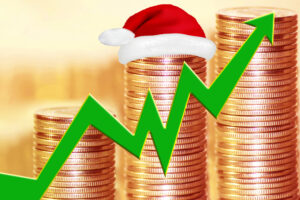 A stack of coins trending upward with an arrow and a Santa Claus hat sitting on the coins.