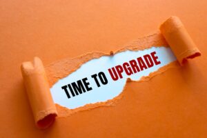 A tear through a piece of orange construction paper, revealing “time to upgrade” in black and red text.