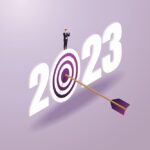 A man standing on top of numbers that read “2023” with a bull’s-eye in the zero.