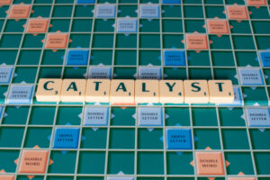 The word “catalyst” spelled out in tiles on a Scrabble board.