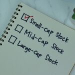 A journal with text and checkboxes written in black marker that list different market cap sizes for stocks. There is a red check next to “small cap stock.”
