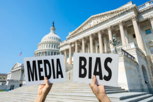 Hands of protestors holding up signs that read “media” and “bias.”