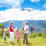 Grandparents with their grandchildren hiking a mountain in a tropical landscape.