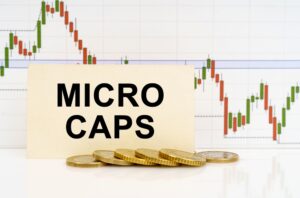 A business card that reads “MICROCAPS” in front of a downward trending line and a stack of gold coins.