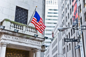 The side entrance of the New York Stock Exchange and a street sign of Wall Street.