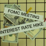 “Interest rate hike” and “FOMC” hanging by clothespins with money in the background.