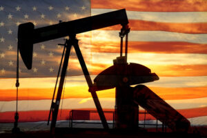 An oil well pumpjack with an American flag in the background.