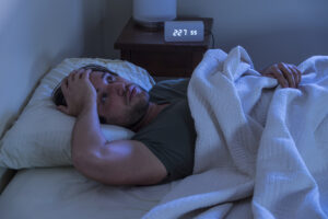 A man in bed having trouble falling asleep.
