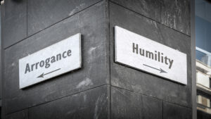 A street sign showing “humility” or “arrogance” in each direction.