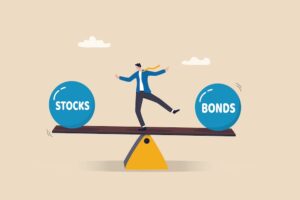 A businessman balancing in between two weights that read "stocks" and "bonds" respectively.