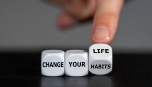 Hand turns dice and changes the slogan “change your habits” to “change your life.”