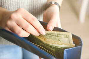A woman pulling cash out of a wallet.