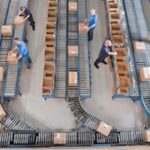 Workers boxing product on a conveyer belt.