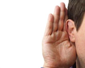 A businessman holding a hand up to his ear.