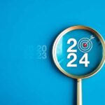 “2024” spelled out inside of a magnifying glass with a bullseye target inside it.