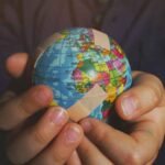 A globe in someone's hands with band aids over it.