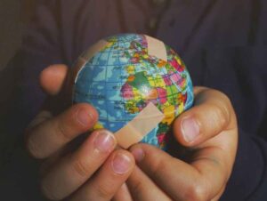 A globe in someone's hands with band aids over it.