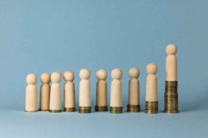 Wooden figurines on top of stacks of coins.