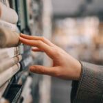 A hand reaching out to touch books on a shelf.